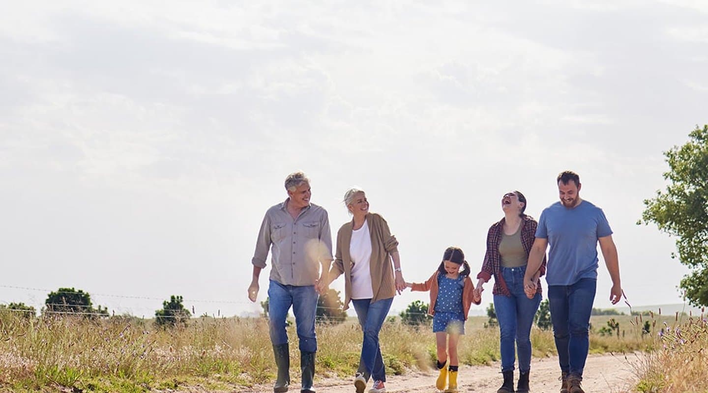 Happy multi-generational family walks through a field