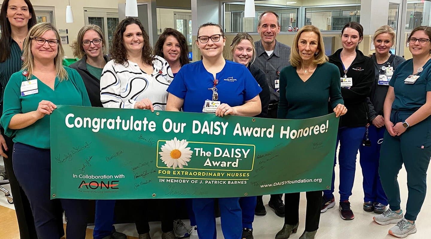 A group stands in front of the DAISY Award banner in the emergency department
