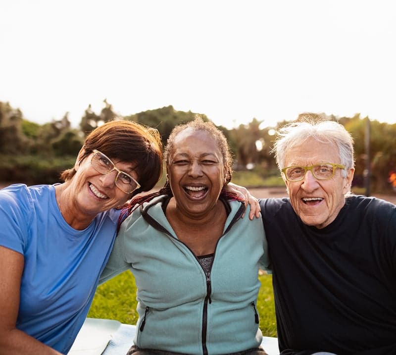 Two women and a man sit outdoors on a sunny day