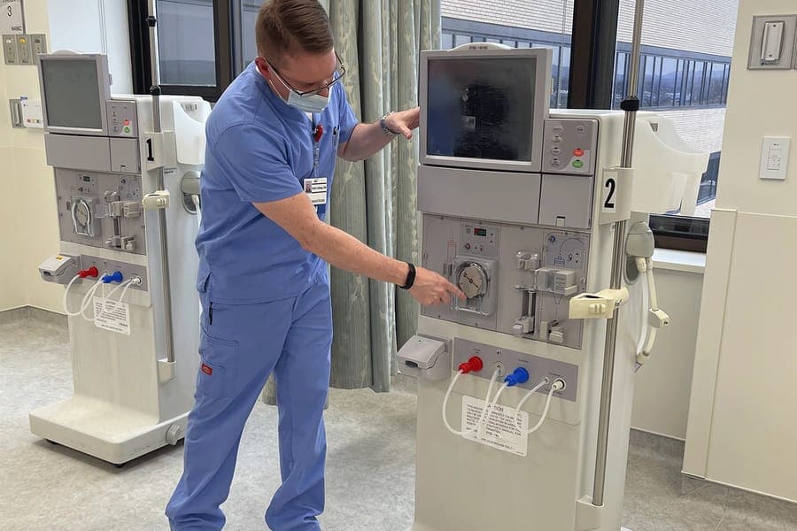 A nurse interacts with the dialysis machinery