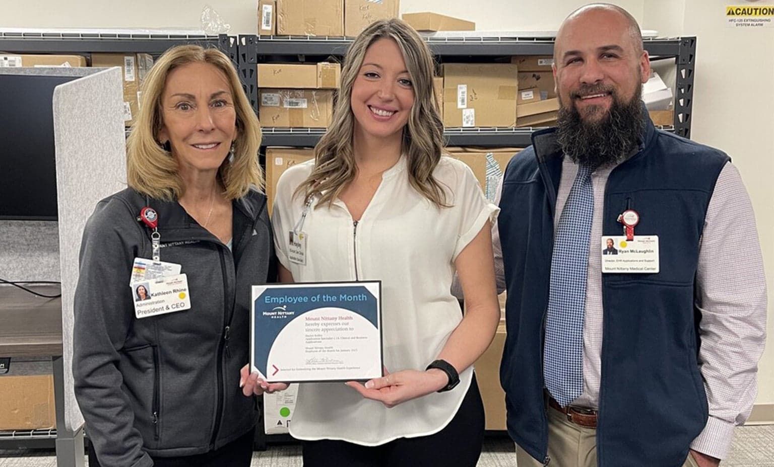 Kathleen Rhine and Ryan McGlaughlin stand with Hayley Kelley while she poses with her Employee of the Month certificate
