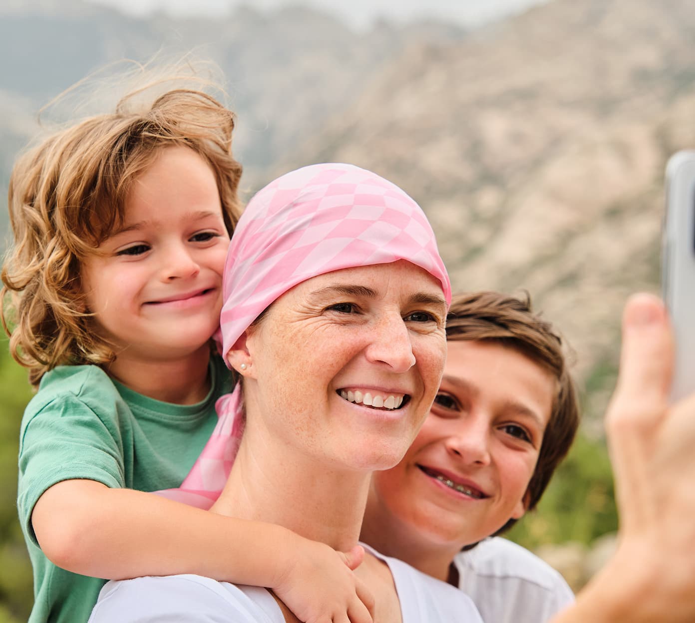 Mother wearing a scarf takes a selfie with her two young children