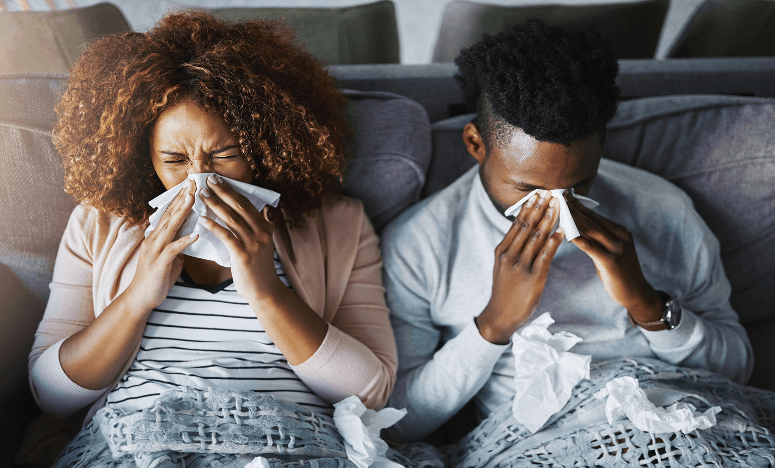 Couple sign in bed blowing their noses.