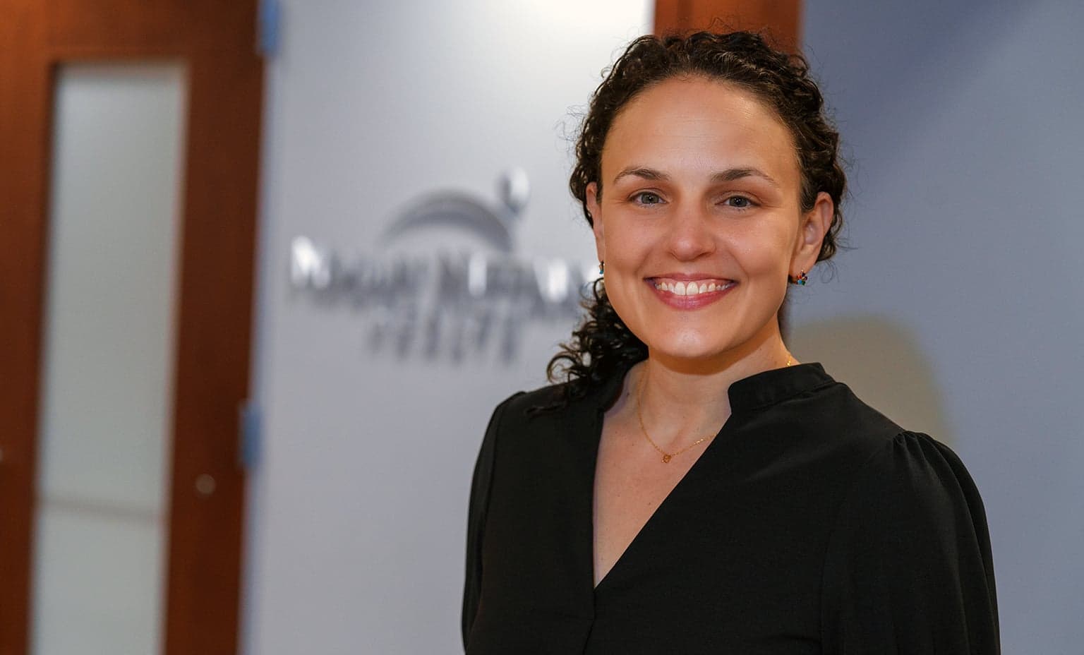 Lorraine Rosamilia, MD smiles outside of an office door