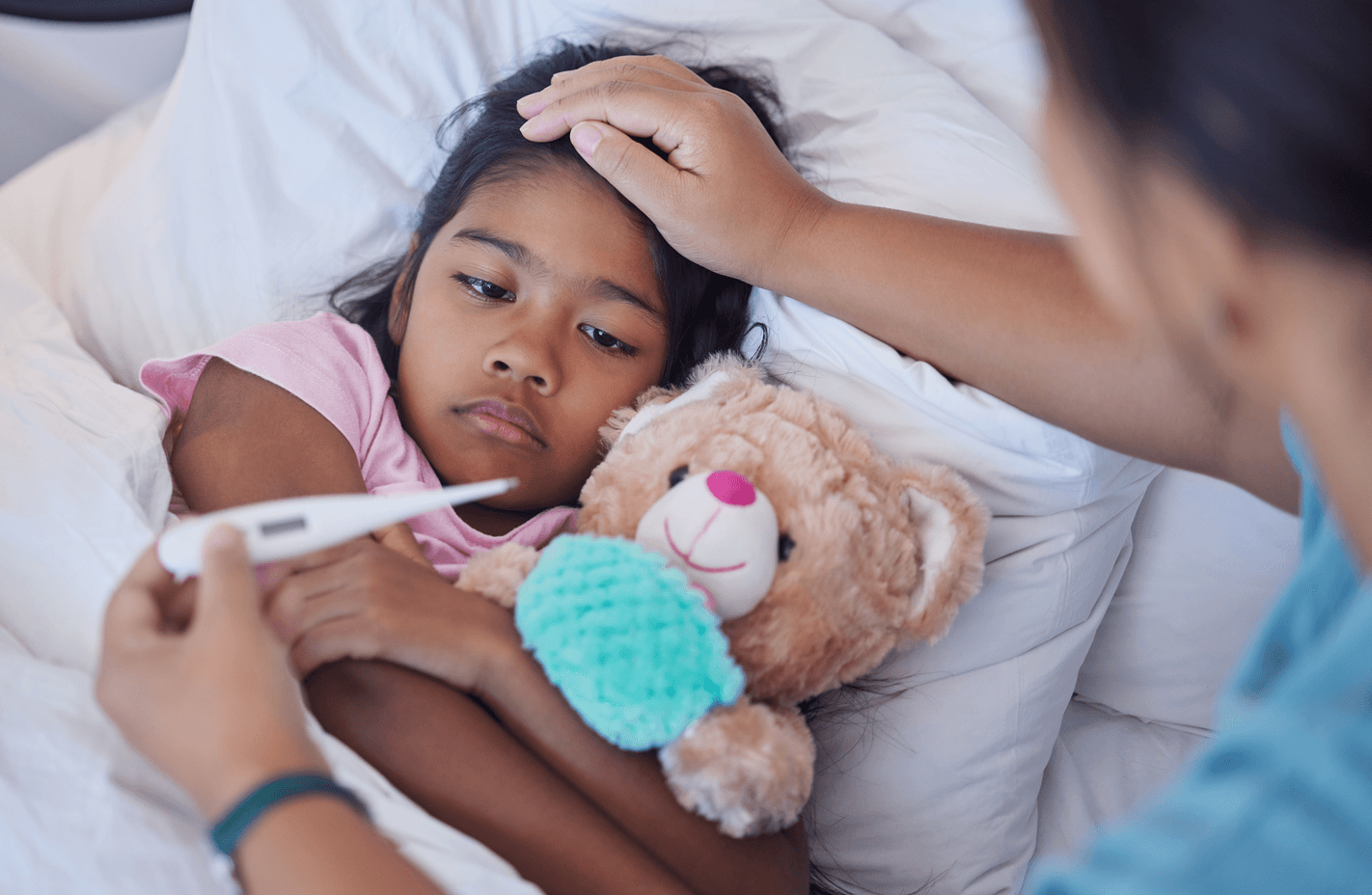 Kid resting while mom takes temperature in bedroom