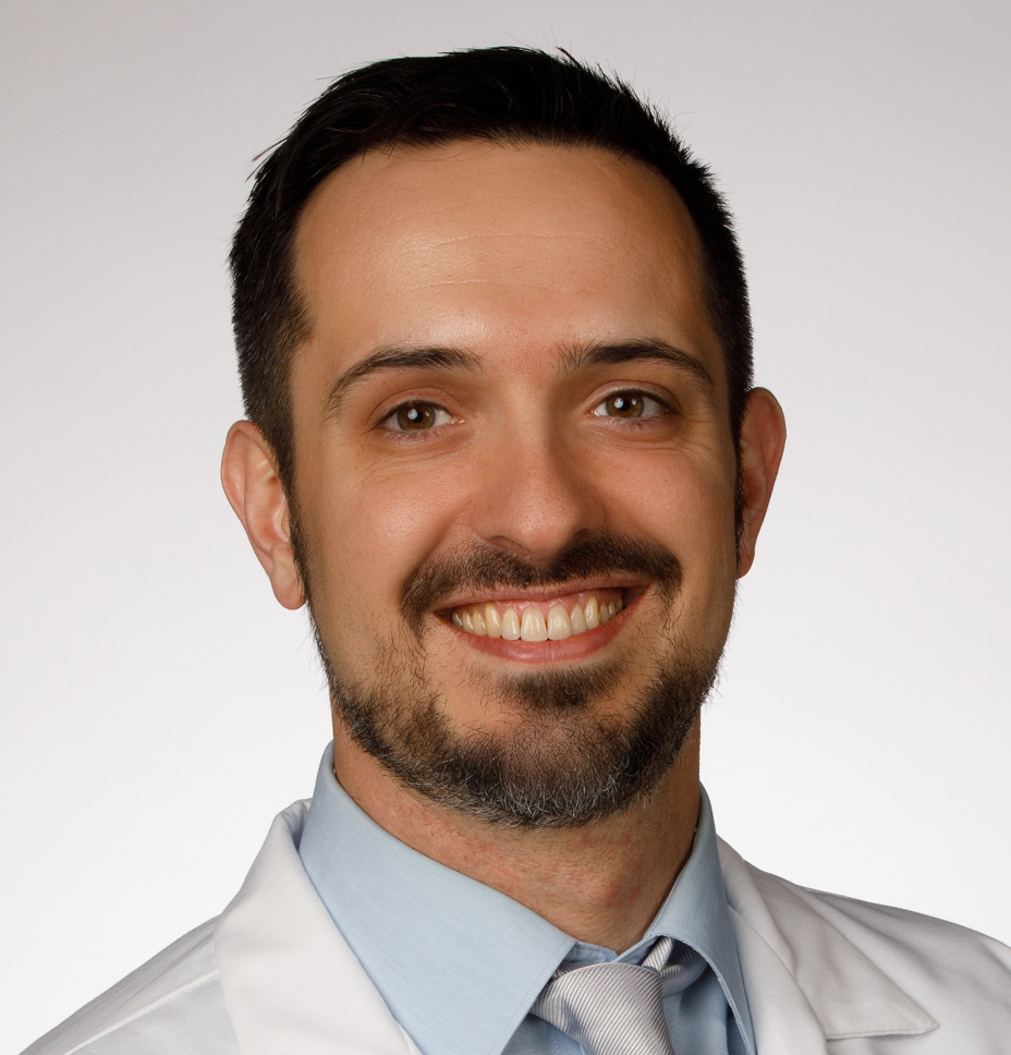 Paul Baresal, hospitalist, poses for a professional headshot while wearing his whitecoat