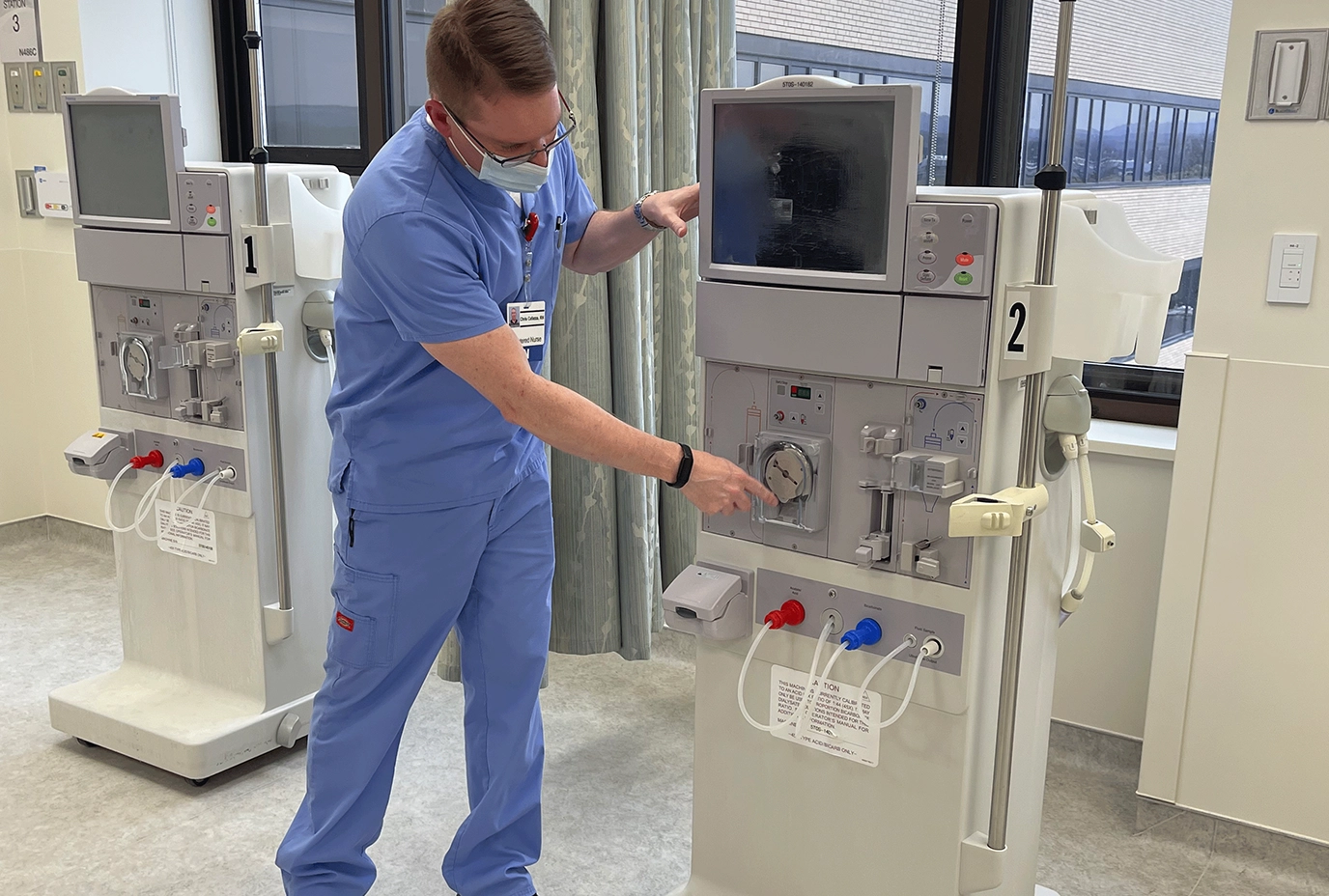A nurse interacts with the dialysis machinery