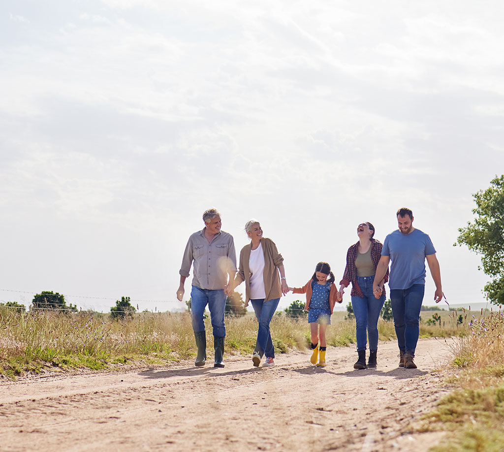 Happy multi-generational family walks through a field