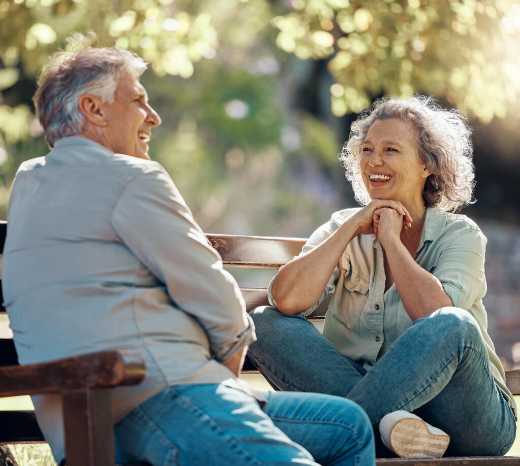 Women and man sit outside on a bench