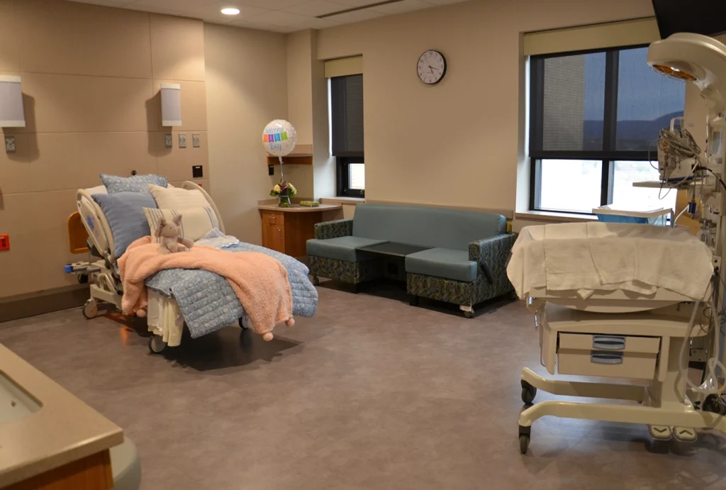 Typical room in the women and children's unit with a comfortable bed, couch, and space for the new baby
