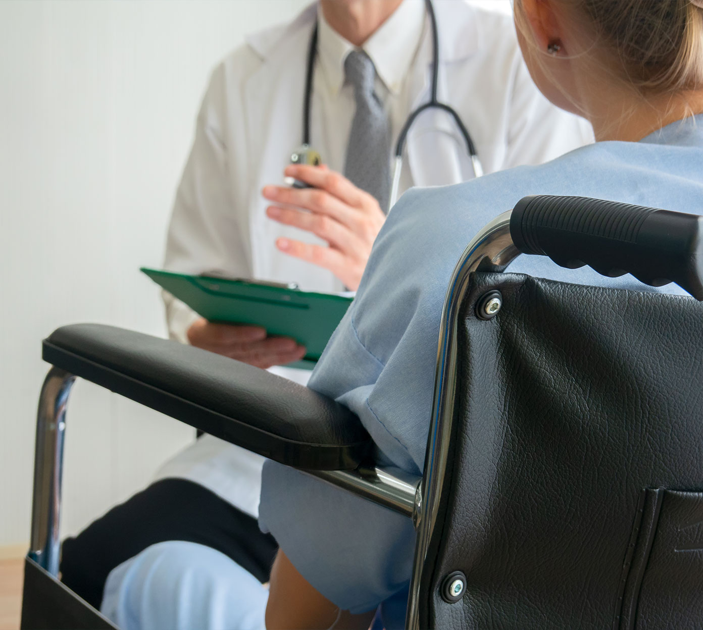 Physician sits in front of a patient holding paperwork