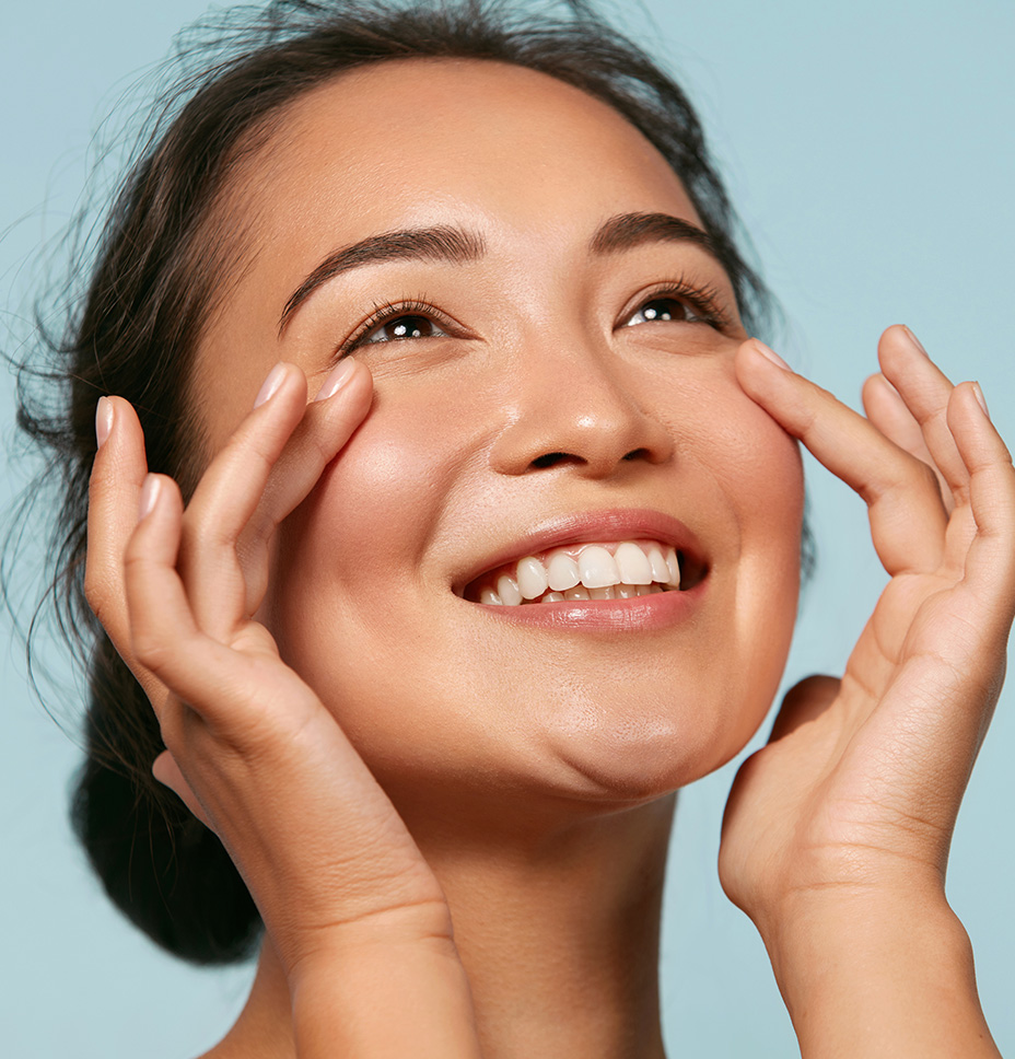 Young asian woman smiles and touches her face because she has great skin