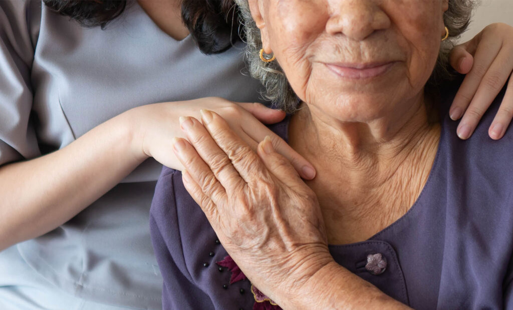 Woman comforts older woman by placing hands on her shoulders