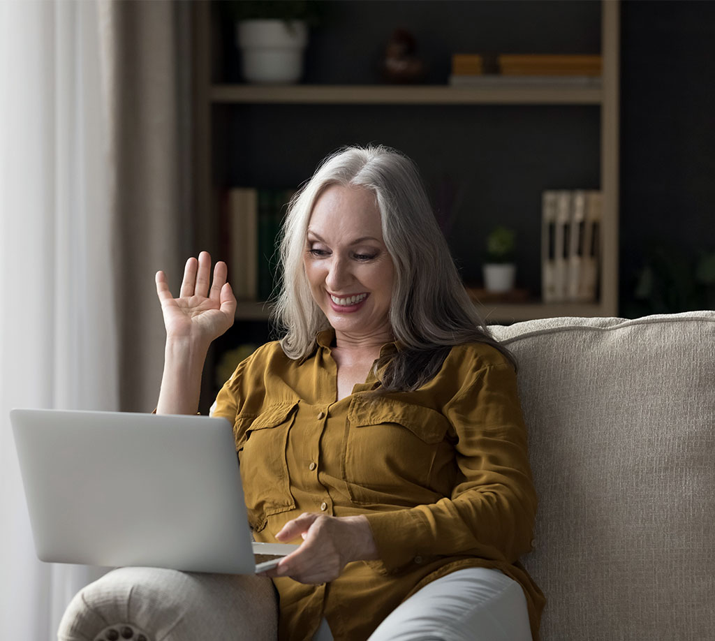 woman smiles at her laptop during a telehealth appointment