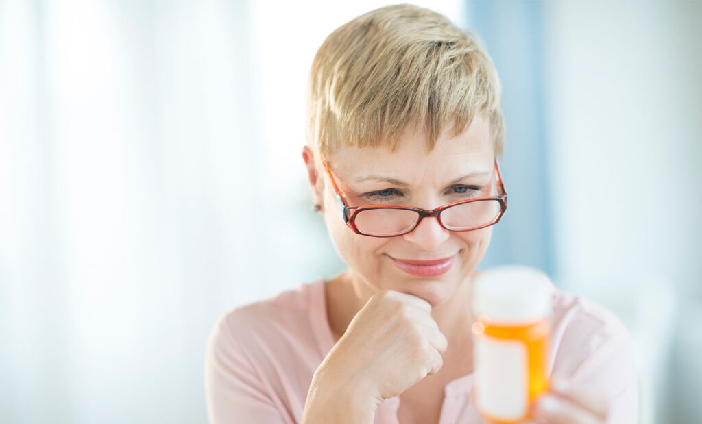 Woman reads prescription bottle label which is important to health literacy