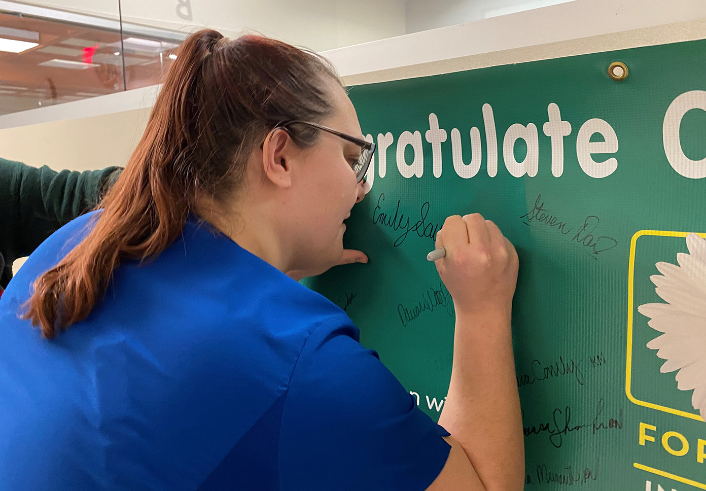 Emily Savering signs the DAISY award banner