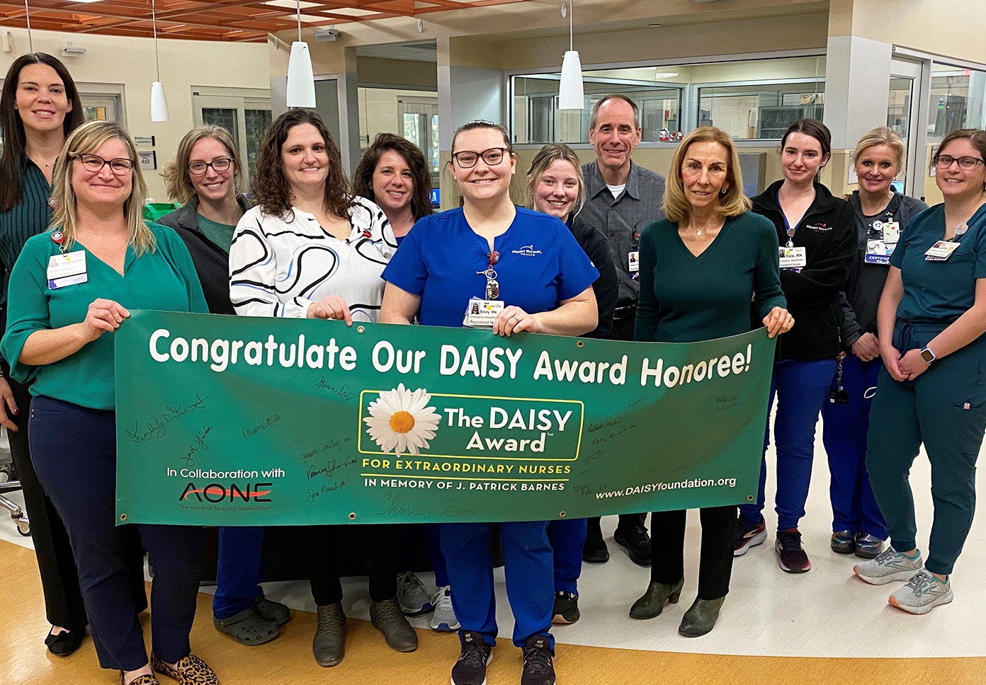 A group stands in front of the DAISY Award banner in the emergency department