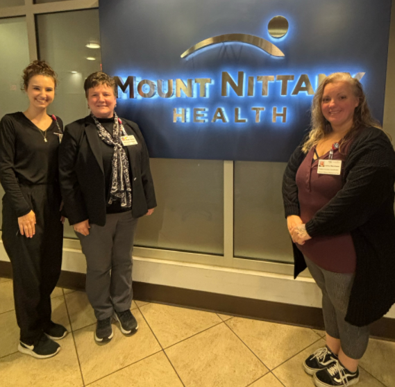 Patient Access team members stand in front of the Mount Nittany Health logo wall