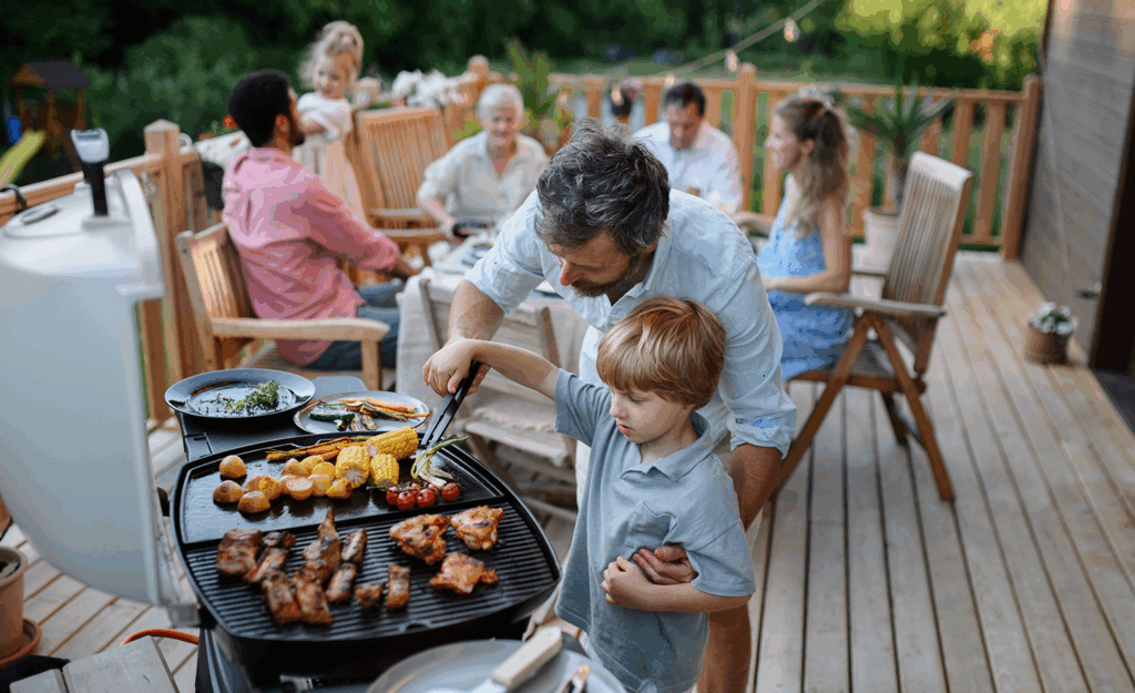 Father grilling with young son on deck during summer day