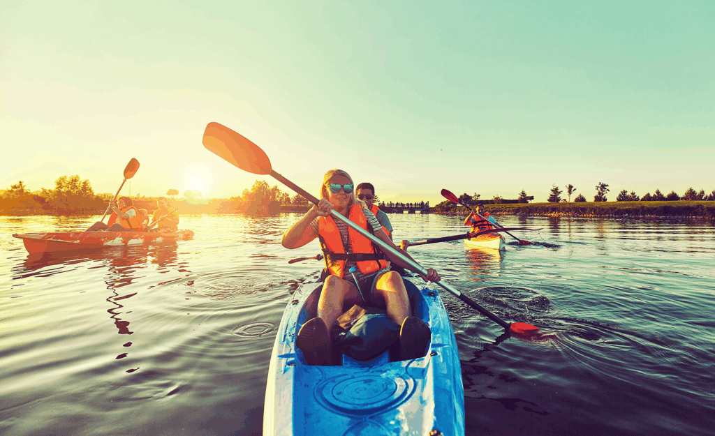 6 people kayaking in three separate kayaks during sunset