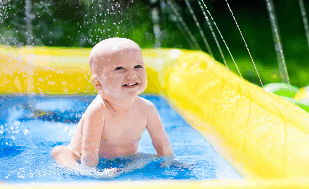 baby sitting in kid pool outside, smiling