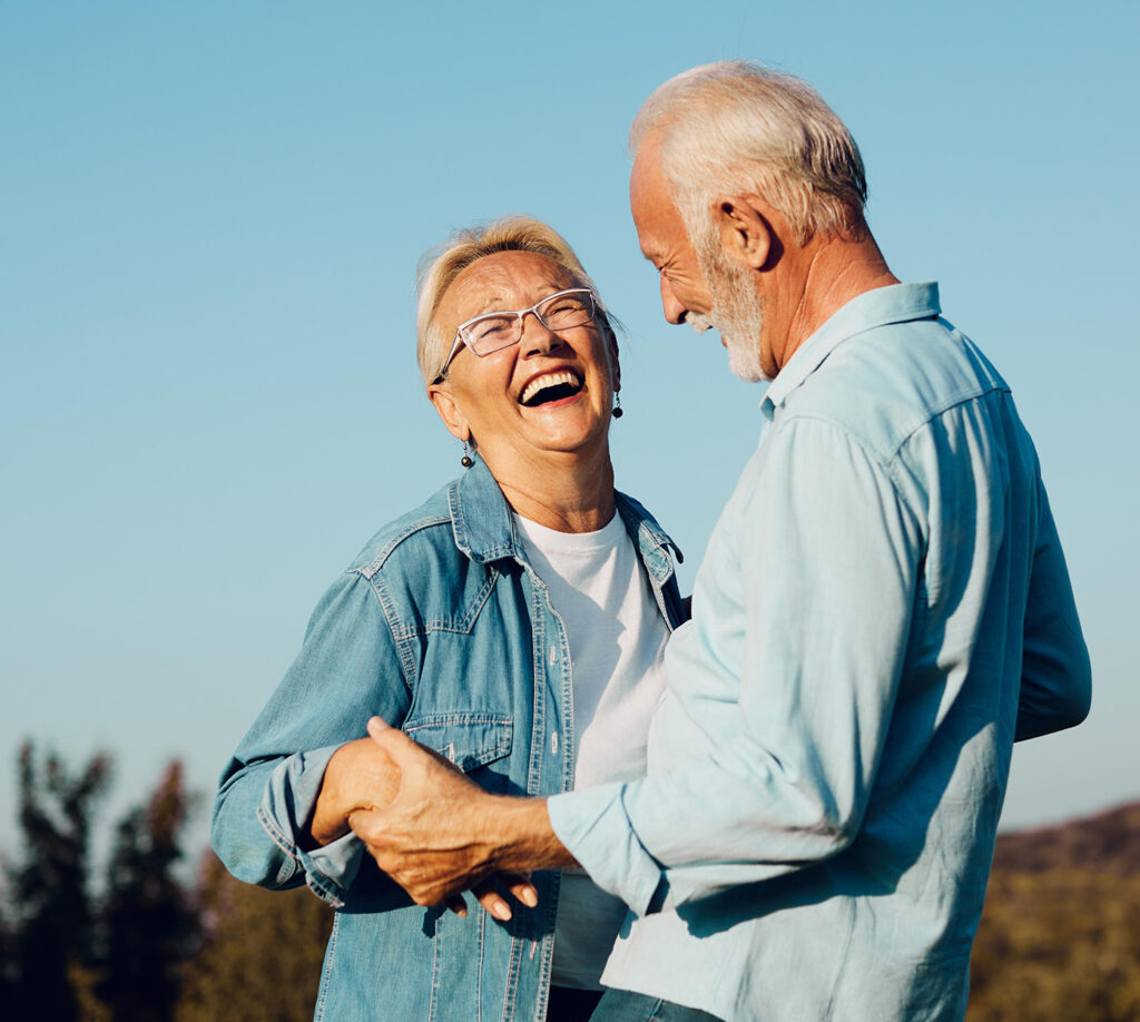 Woman and man stand outside smiling and wearing denim