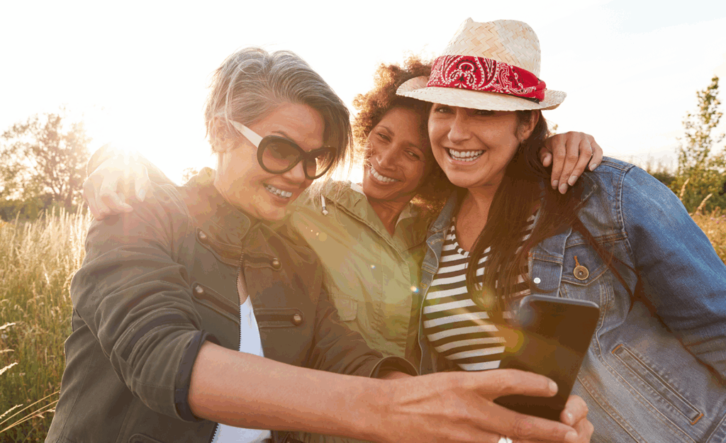 three middle aged women posing for a selfie in field