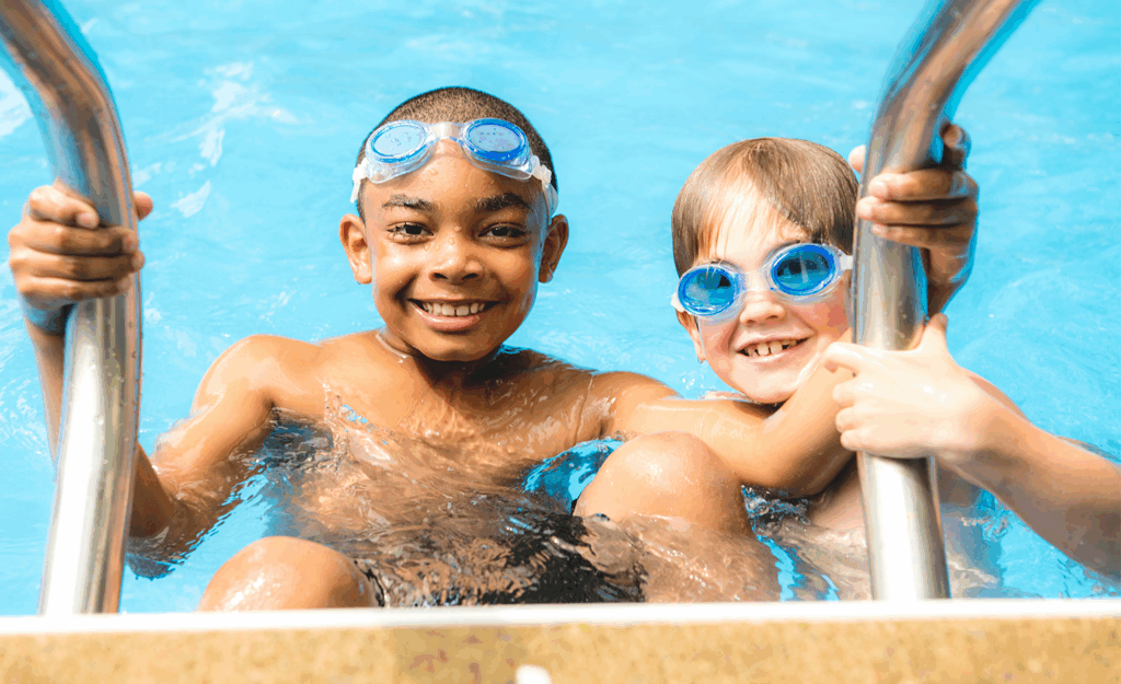 two tween boys playing in outside swimming pool - smiling at camera
