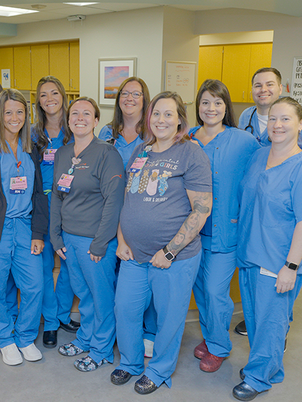 medical professional in scrubs stand and smile for group picture