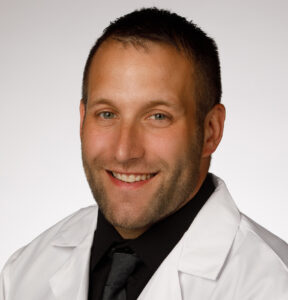 Leonard Shamus wears his white coat and smiles for a professional headshot.