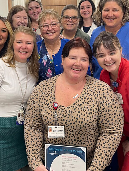 A group of people gather for a photo with Sallee Hart, employee of the month winner