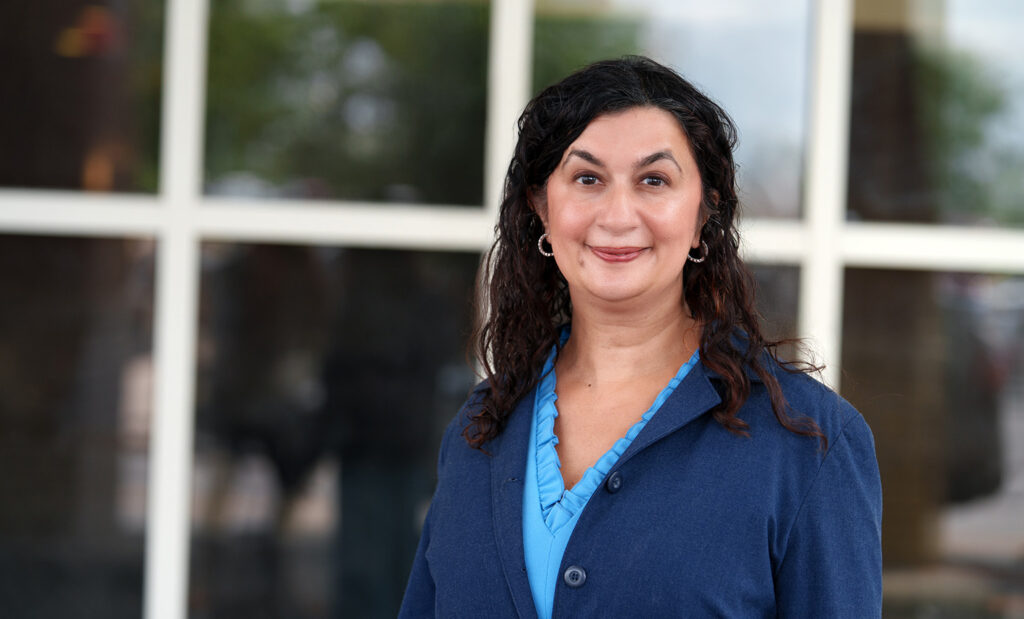 Asna Amin, MD poses in front of a window for an outdoor photo