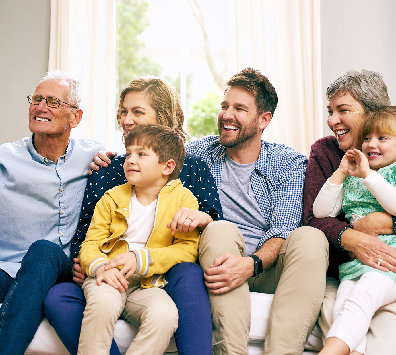 a multigenerational family sits on a couch and smiles for a picture