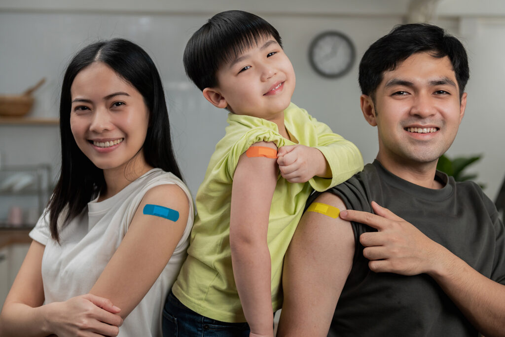 Mom, dad, and child post with their band aids after getting flu shots in the arms