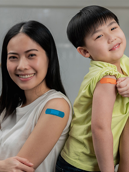 Young mother and son pose with their bandaids on their arms after receiving their flu shots