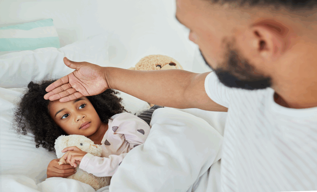 Father checking sick daughter's temperature in bedroom, showing care and concern during flu illness at home.
