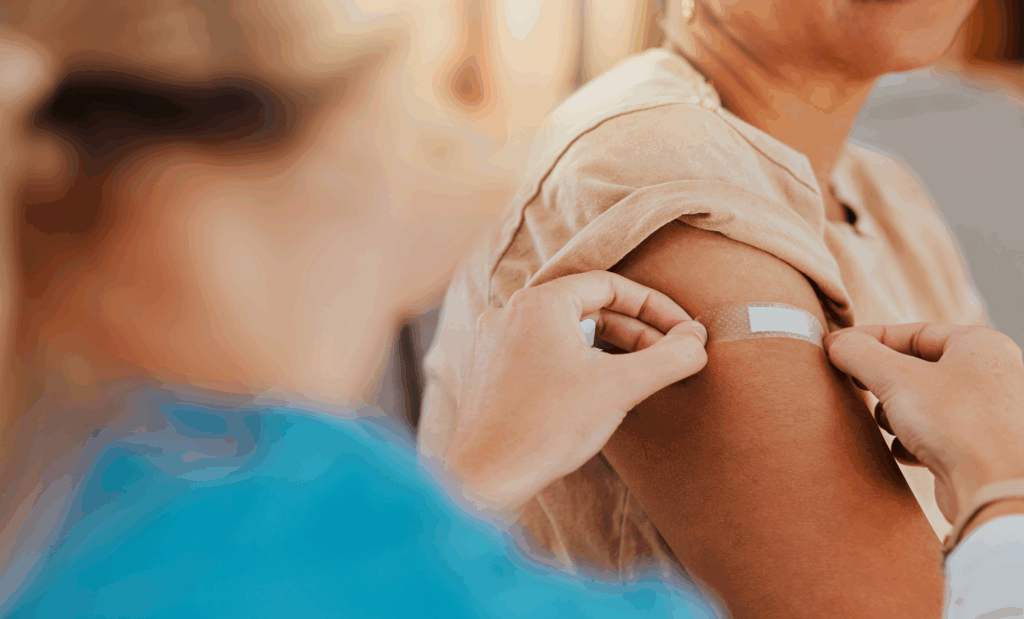 Nurse placing bandage on patient's upper arm after flu shot.