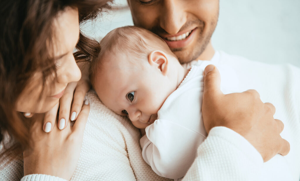newborn lays his head on their father's shoulder while mom watches