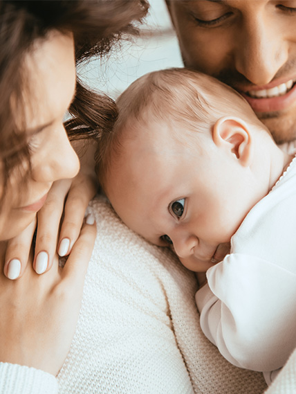 newborn lays his head on their father's shoulder while mom watches