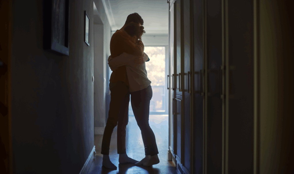 Couple hugging in a hallway.
