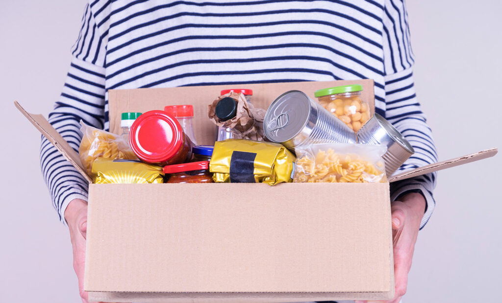 Person wearing a striped shirt holds cardboard box of donated food