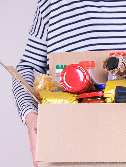 Person wearing a striped shirt holds cardboard box of donated food