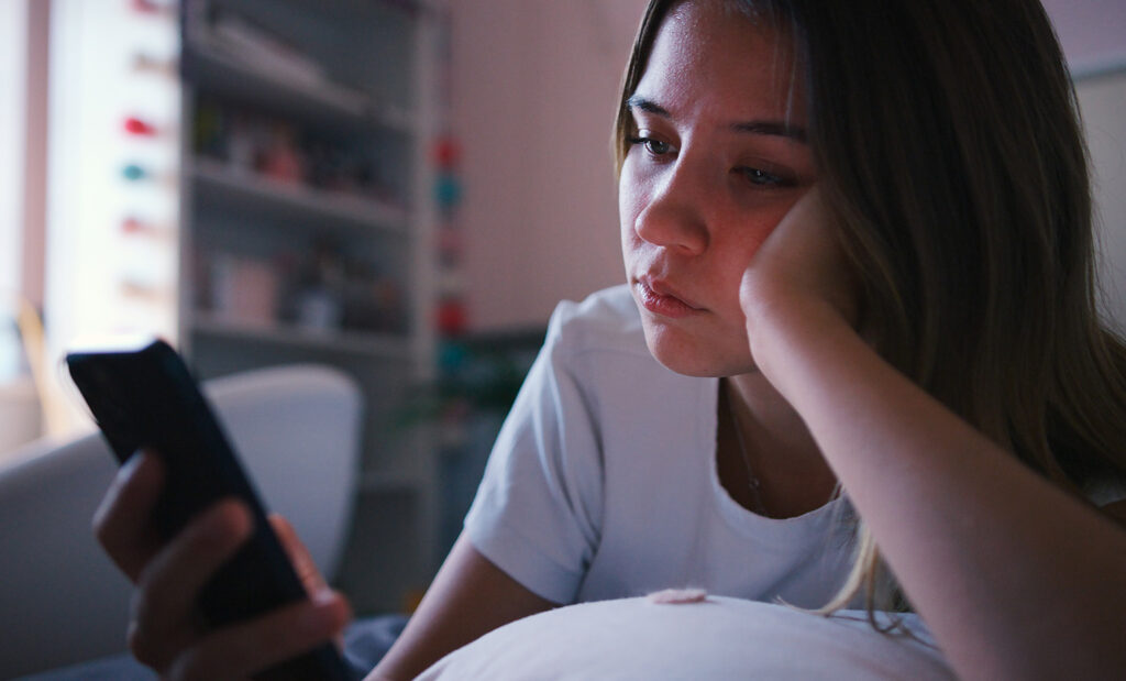 female teenager stares at a smartphone
