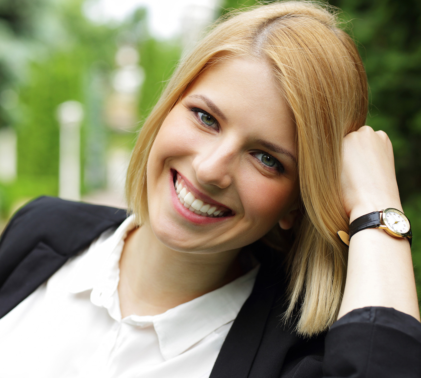 Blonde woman wearing a blazer smiles outside