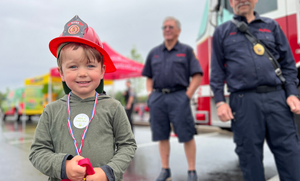 Kid wearing a fireman's hat smiles during Mount Nittany Health Community Day