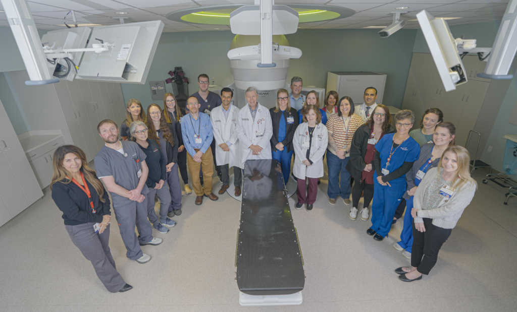 cancer care team stands in front of TrueBeam linear accelerator
